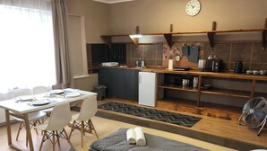 Quarto de hotel compacto com cozinha compacta, área de refeições e cama com toalhas enroladas.