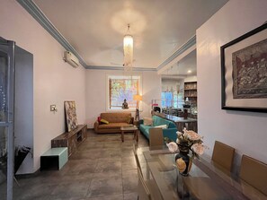 Una sala de estar con un sofá, una mesa de centro de vidrio y un florero con flores.