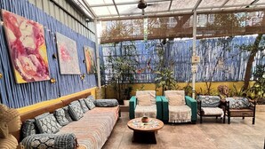 A covered patio area with seating arrangements, including sofas and chairs, and a Buddha statue.