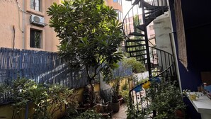 A narrow pathway with potted plants and a spiral staircase.