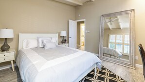 Quarto com cama grande, abajures, ventilador de teto e espelho.
