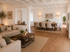A spacious living area with a sofa, coffee table, and dining table set for six. - Villa des Vignes in Cabrials – private pool in the heart of the vineyards (Beziers)