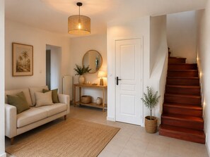A living room with a sofa, a table with a lamp, a mirror, and a staircase. - Villa des Vignes in Cabrials – private pool in the heart of the vineyards (Beziers)