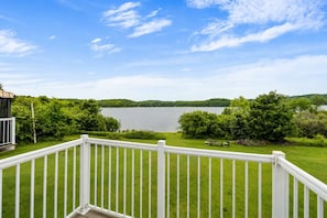 A deck with a white railing overlooking a lake, surrounded by greenery. - Le Repos de L'Ours | Waterfront Chalet with Private Dock (Notre-Dame-de-Pontmain)