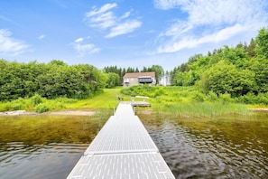 A house with a dock extending into a river, surrounded by lush greenery.