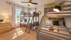 A bunk bed room with a ladder, a desk, and a lamp.