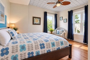 A bedroom with a bed, a chair, a ceiling fan, and windows with curtains. - Le Repos de L'Ours | Waterfront Chalet with Private Dock (Notre-Dame-de-Pontmain)