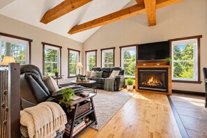 A spacious living room with a fireplace, leather sofas, and large windows.