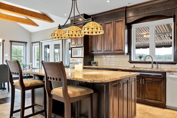A modern kitchen with dark wood cabinets, a granite countertop, and pendant lighting.