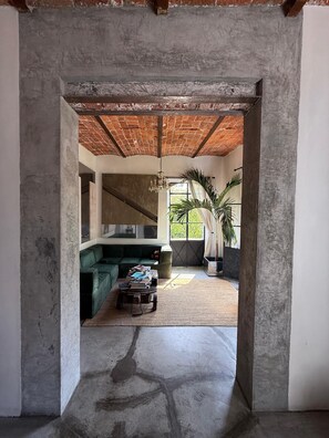 A spacious living area with a green sofa, a coffee table, and a potted plant. - Zacatecas 167, Industrial charm and vintage style in the heart of Roma Norte (Ciudad de México)