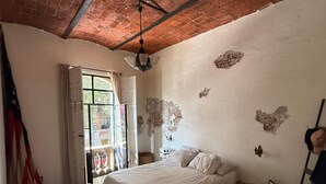 Ein Schlafzimmer mit einem Bett, einem Fenster, einer Hängelampe und einer Ziegeldecke.