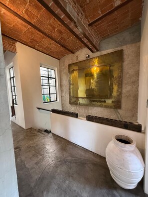 A room with a high ceiling, exposed brick walls, a large window, and a white ceramic pot. - Zacatecas 167, Industrial charm and vintage style in the heart of Roma Norte (Ciudad de México)