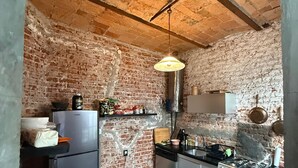 Eine Küche mit Backsteinwand, Kühlschrank, Herd und einer Pendelleuchte.