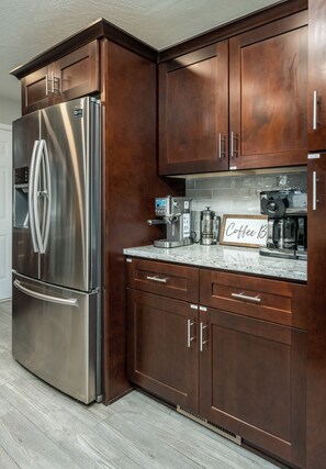 A kitchen with dark wood cabinets, stainless steel appliances, and a marble countertop. - Relax In Sedona/Thunder Mountain View-FLAT (Sedona)