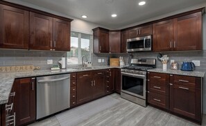 A modern kitchen with dark wood cabinets, stainless steel appliances, and a granite countertop. - Relax In Sedona/Thunder Mountain View-FLAT (Sedona)