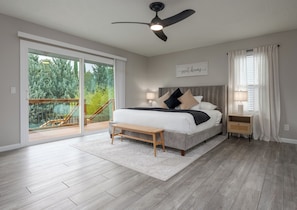 Een slaapkamer met een bed, nachtkastjes, een plafondventilator en uitzicht op een balkon.