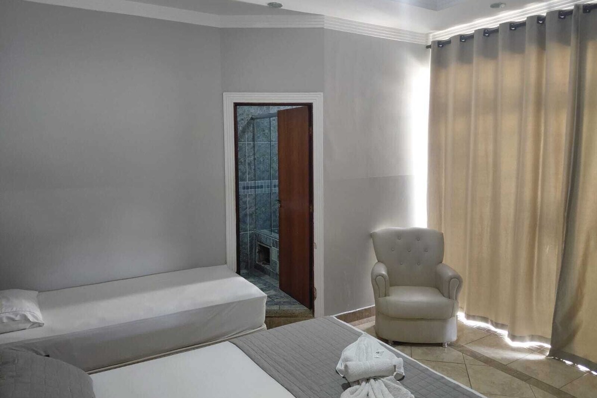 A hotel room with a bed, a chair, and a view of a tiled area through a door.