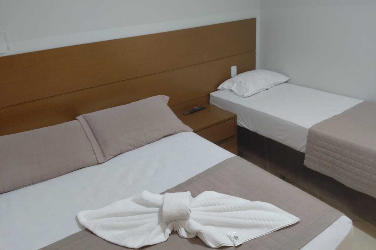 A hotel room with a bed, a nightstand, and a bedside table.