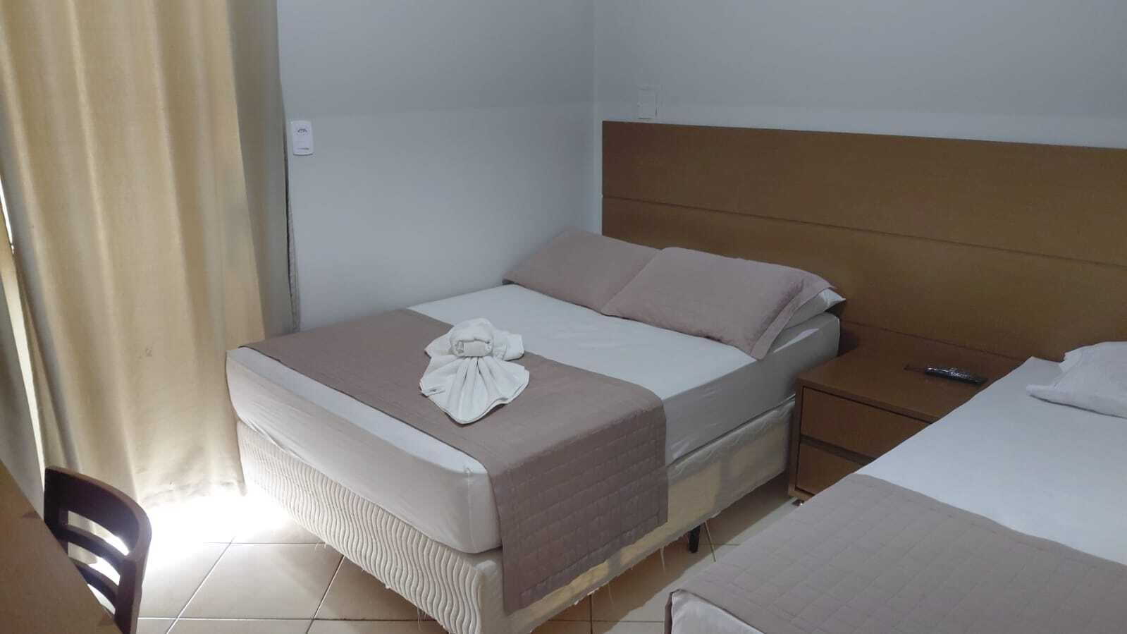 Una cama individual con cabecera, mesita de noche y una silla.