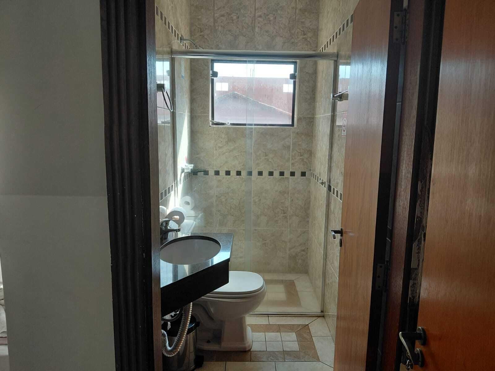 Casa de banho com chuveiro, sanita e lavatório.