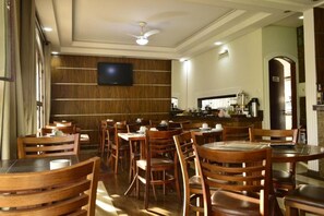 A restaurant with wooden furniture, a flat-screen TV, and a kitchen area. - Hotel Requinte Careaçu (Careaçu)