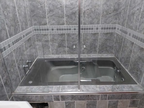 A bathroom with a glass-enclosed bathtub, tiled walls, and a shower area. - Hotel Requinte Careaçu (Careaçu)