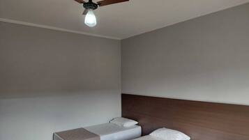 A room with two beds, a ceiling fan, and a light fixture.
