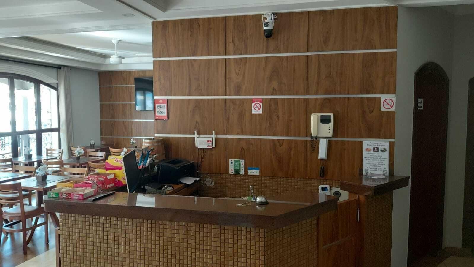 A hotel reception area with a wooden reception desk, a telephone, and a sign indicating no smoking.