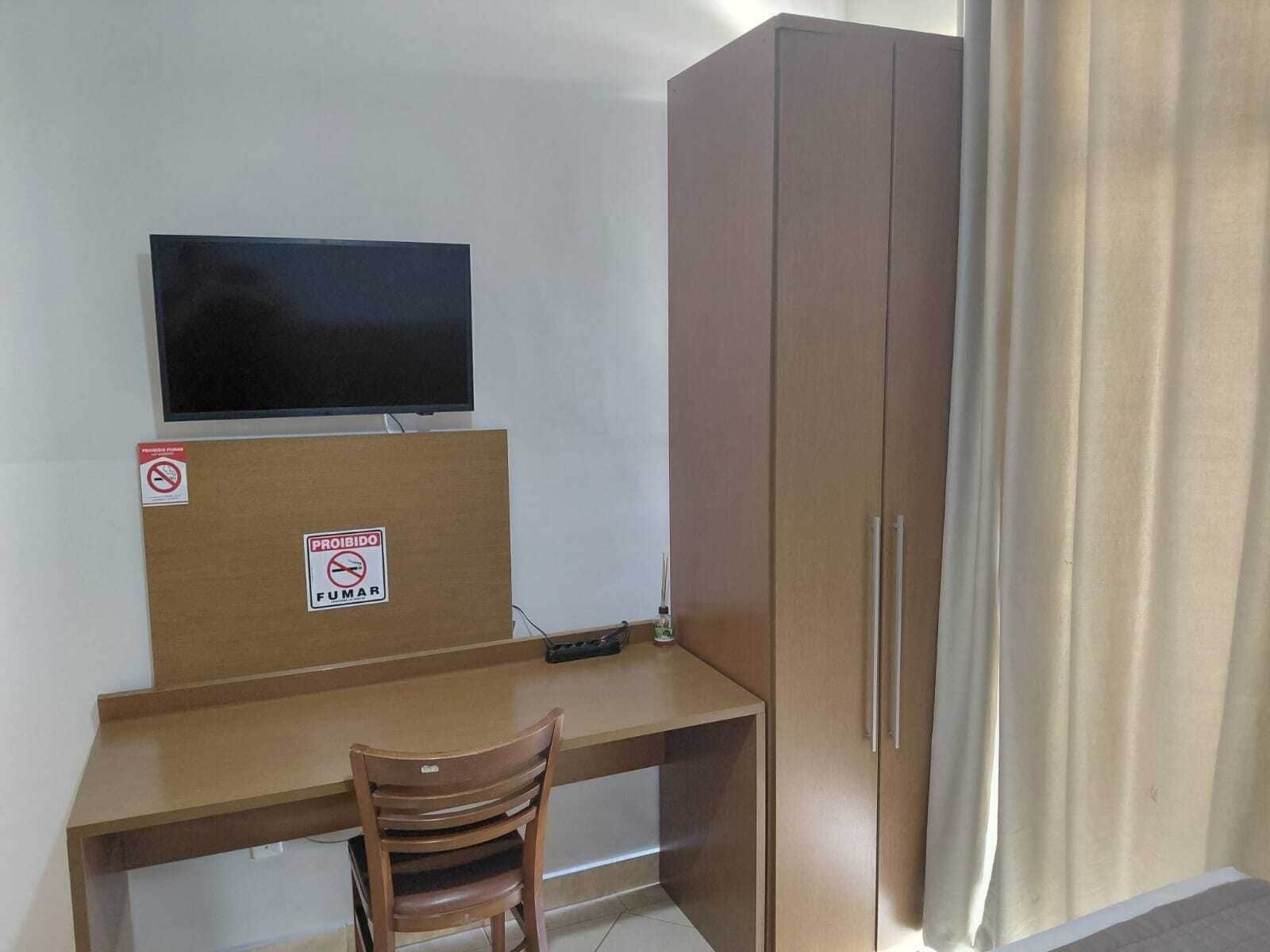 Una habitación con escritorio, televisión, armario y una silla.