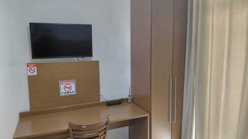 Una habitación con escritorio, televisión, armario y una silla.