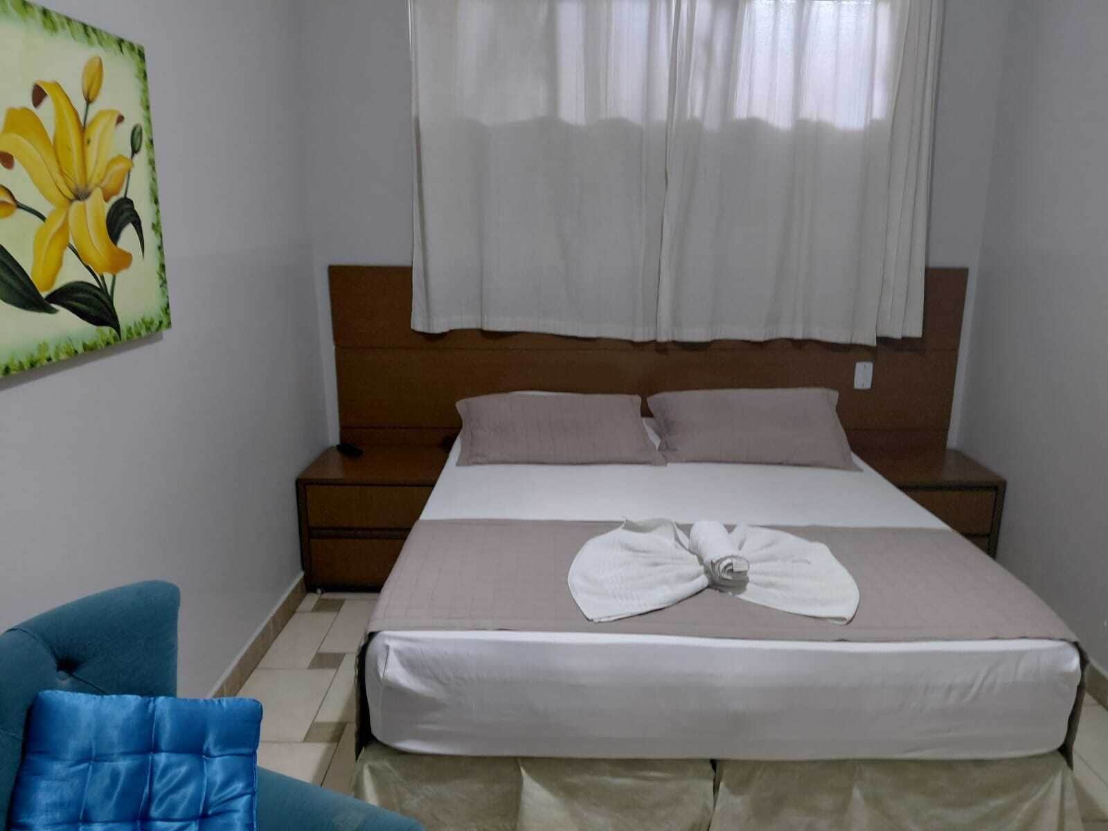 A bedroom with a bed, a nightstand, a chair, and a painting on the wall.