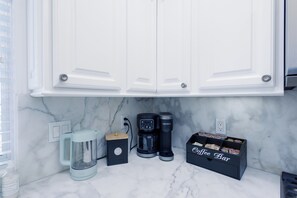 A kitchen with white cabinets, a coffee maker, a coffee grinder, a coffee pot, and a coffee bar box. - BeachRentalCarlsbad - 180° Ocean Views - 5 Min Walk to the Beach - Sleeps 7 (Carlsbad)