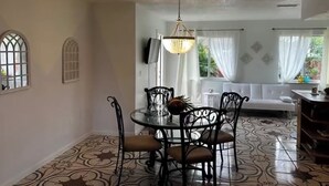 En matplats med ett runt bord, stolar, en kristallkrona och en soffa i bakgrunden.