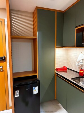 Eine kleine Küche mit einem eingebauten Kühlschrank, einer Mikrowelle und einem Spülbecken.