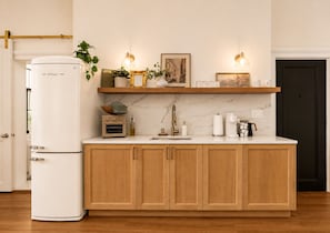 A kitchen with wooden cabinets, a white refrigerator, a coffee maker, and a shelf with decorative items.