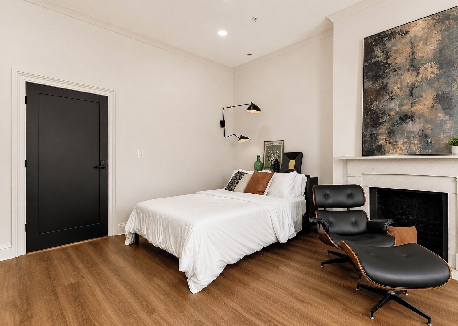 Un dormitorio con una cama, una silla, una chimenea y un cuadro en la pared.