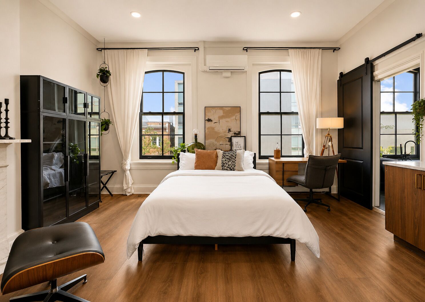 A modern bedroom with a large bed, a desk, and a wardrobe.