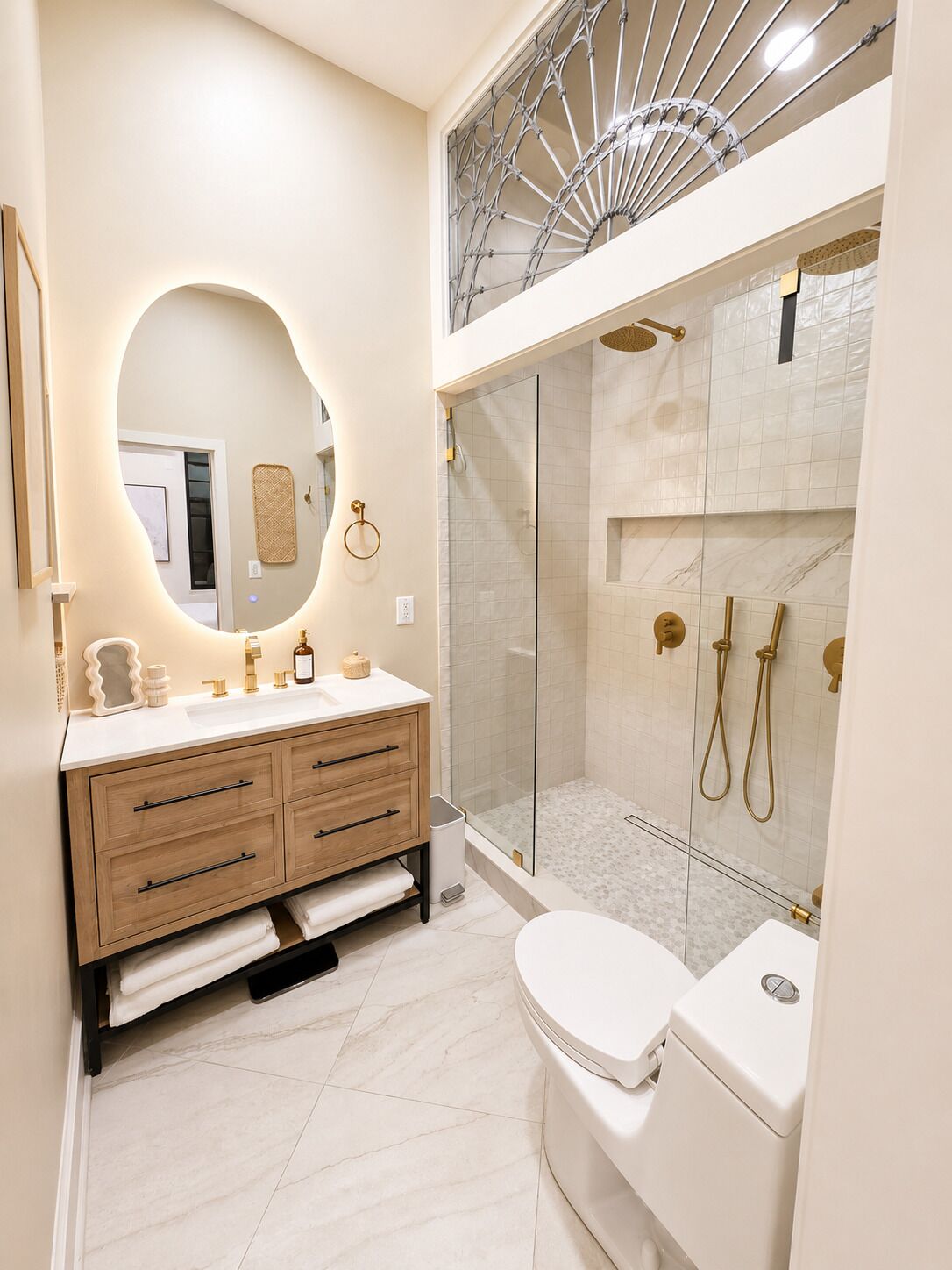 A modern bathroom with a vanity, a toilet, a shower enclosure, and a large mirror.