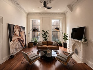A living room with a fireplace, a large painting, and two floor lamps. - The Marle (Baltimore)