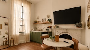 A cozy living room with a fireplace, a television mounted above it, and a dining area with a round table and chairs. - The Marle  (Baltimore)
