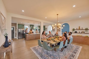 A modern kitchen with a central island, dining area with chairs, and a decorative wall. - Lakefront home · hot tub, arcade, fire pit (Long Pond)