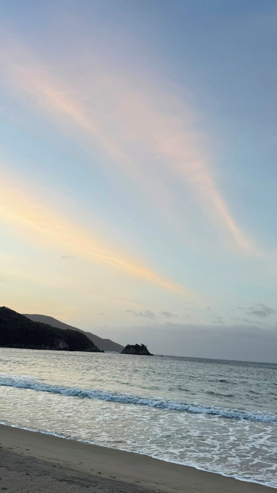 A beach with gentle waves and a clear sky.