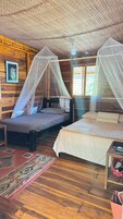 Habitación con dos camas, cada una con dosel, paredes de madera y alfombra estampada.