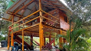 A wooden structure with a covered seating area, surrounded by natural vegetation. - CABAÑA LA JULIANA (Neguanje)