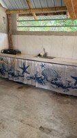Una cocina con salpicadero de azulejos, cocina a gas, lavabo y ventana con vistas a zonas verdes.
