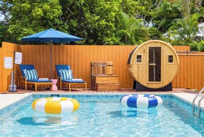 Ein Swimmingpool mit Liegestühlen und einer Sauna.