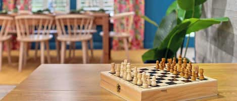 Un tablero de ajedrez sobre una mesa de madera en una habitación con pared azul y cortinas con motivos florales.
