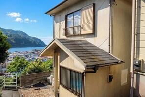 Ein Wohngebäude mit geneigtem Dach, einem Balkon und Blick auf eine Küstenstadt.