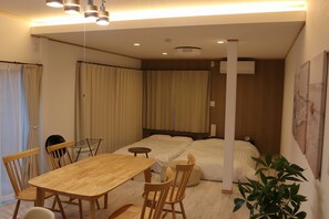 A hotel room with a wooden dining table, two beds, a fan, and a potted plant. - A private villa with an open-air hot spring bath offering panoramic views of the ocean and the port town! Complete with a slide and a movie projector—enjoy a special getaway for up to 8 guests (Inatori, Higashiizu, Kamo District)