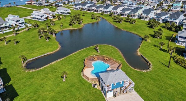 Ett bostadsområde med en stor damm, hus och en swimmingpool.